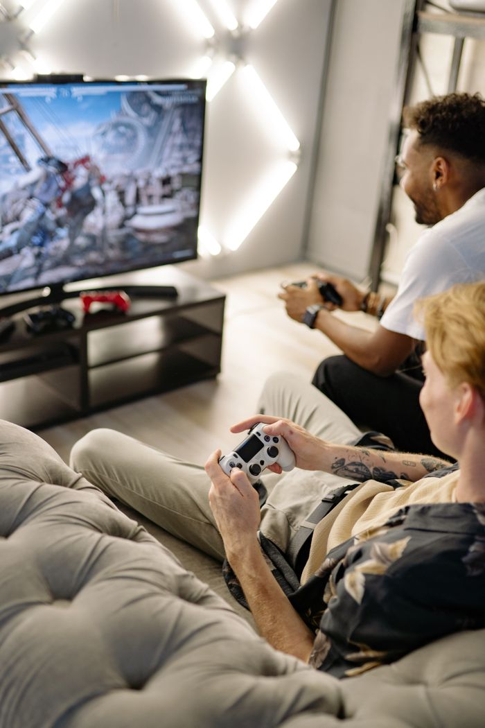 Two friends playing video games at home, immersed in a gaming session with controllers and a big screen.